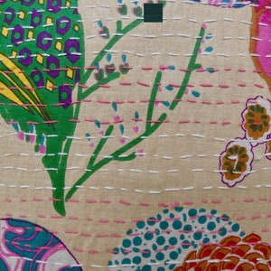 Puede incluir: Una tela beige con un estampado floral colorido. La tela presenta una variedad de flores, hojas y formas geom&eacute;tricas en tonos de rosa, verde, azul, amarillo y naranja. La tela est&aacute; cosida con hilo blanco y rosa, creando un efecto acolchado.