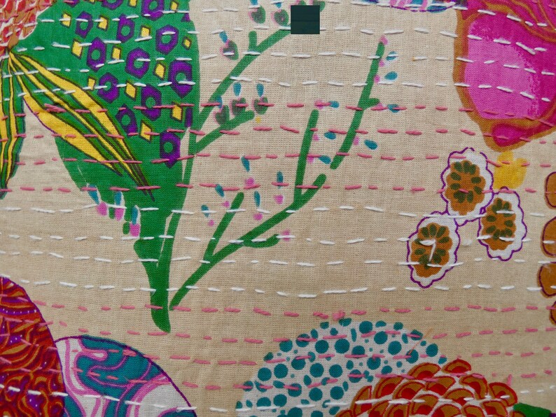 Puede incluir: Una tela beige con un estampado floral colorido. La tela presenta una variedad de flores, hojas y formas geom&eacute;tricas en tonos de rosa, verde, azul, amarillo y naranja. La tela est&aacute; cosida con hilo blanco y rosa, creando un efecto acolchado.