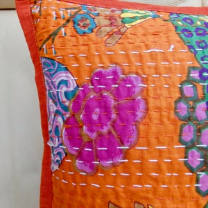 Peut inclure: Coussin carr&eacute; orange avec un motif floral rose, vert et bleu. Le coussin pr&eacute;sente un motif cousu avec une bordure orange unie.