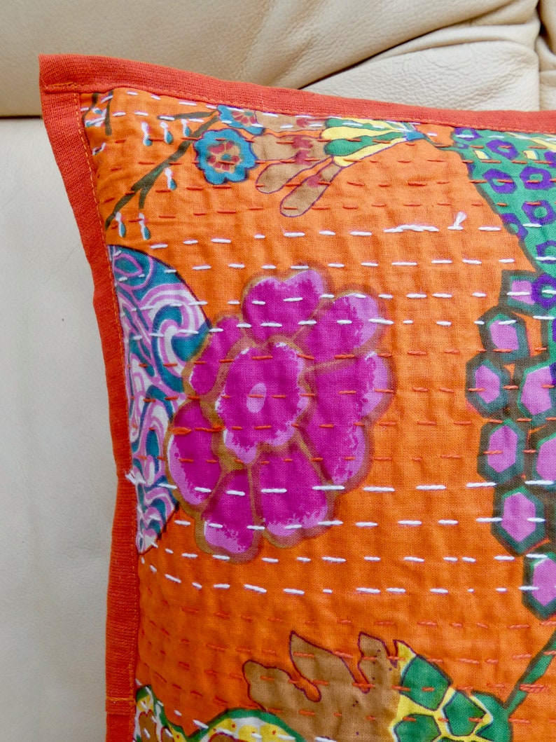 Peut inclure: Coussin carr&eacute; orange avec un motif floral rose, vert et bleu. Le coussin pr&eacute;sente un motif cousu avec une bordure orange unie.