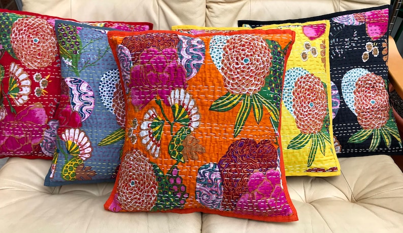 K&ouml;nnte beinhalten: F&uuml;nf bunte Kissen mit Blumenmustern. Die Kissen sind auf einem wei&szlig;en Sofa angeordnet. Die Kissen sind aus einem weichen, gesteppten Stoff gefertigt. Die Kissen sind in verschiedenen Farben, darunter Rot, Blau, Orange, Gelb und Schwarz.