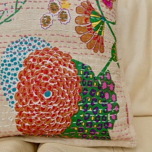 Puede incluir: Una funda de coj&iacute;n de algod&oacute;n beige con un patr&oacute;n floral. El patr&oacute;n presenta flores rosas, rojas, naranjas, verdes, azules y amarillas. La funda de coj&iacute;n est&aacute; acolchada con hilo blanco.