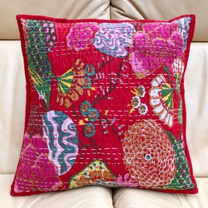 K&ouml;nnte beinhalten: Roter Baumwoll-Kissenbezug mit einem floralen Muster in Rosa-, Gr&uuml;n- und Gelbt&ouml;nen. Der Kissenbezug ist gesteppt und hat einen roten Rand.