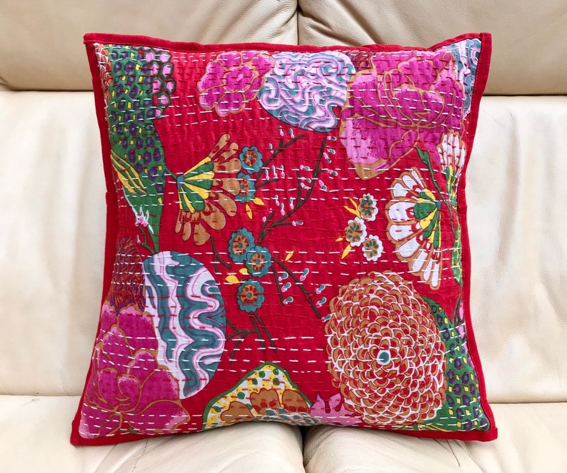 K&ouml;nnte beinhalten: Roter Baumwoll-Kissenbezug mit einem floralen Muster in Rosa-, Gr&uuml;n- und Gelbt&ouml;nen. Der Kissenbezug ist gesteppt und hat einen roten Rand.