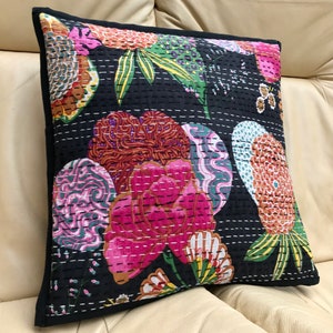 May include: Black cotton pillow cover with a floral pattern in shades of pink, green, orange, and purple. The pillow cover is quilted with white thread and has a black border.