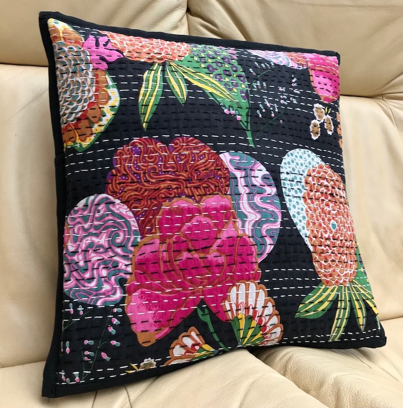 May include: Black cotton pillow cover with a floral pattern in shades of pink, green, orange, and purple. The pillow cover is quilted with white thread and has a black border.
