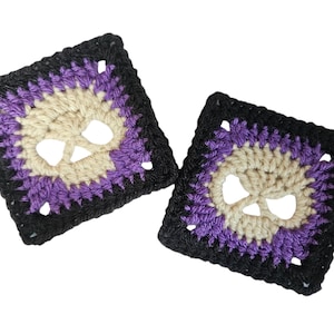 May include: Two square crochet coasters with a skull design. The skulls are beige with purple and black accents. The coasters are handmade and suitable for Halloween or gothic decor.