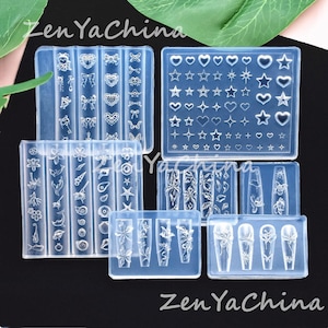 Può includere: Stampi in silicone trasparente per nail art. Gli stampi presentano vari disegni, tra cui fiocchi, cuori, stelle, fiori e forme di unghie. Il testo "Zen Ya China" è visibile nell'immagine.