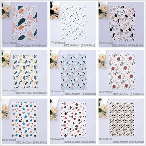 May include: A set of 8 different patterned sheets of paper with a terrazzo design. Each sheet measures 14 cm by 10 cm. The patterns feature various colours including pink, blue, yellow, brown, and white.
