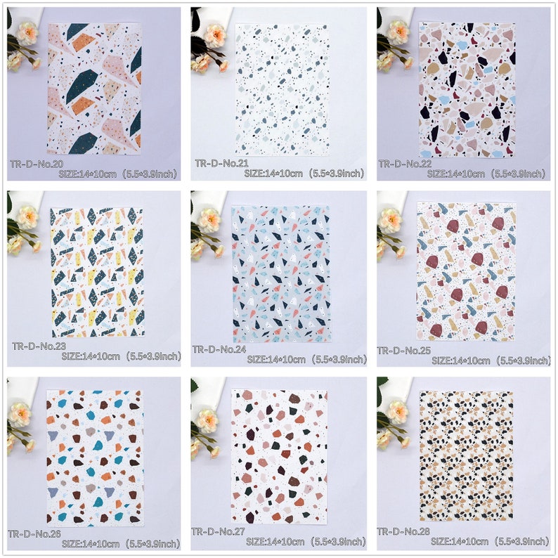 May include: A set of 8 different patterned sheets of paper with a terrazzo design. Each sheet measures 14 cm by 10 cm. The patterns feature various colours including pink, blue, yellow, brown, and white.
