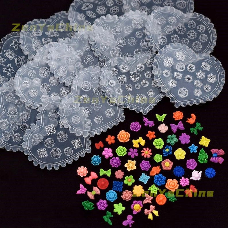 May include: A selection of heart-shaped, clear plastic stencils featuring floral patterns, alongside an assortment of small, colourful flower and bow-shaped decorations. The decorations are in shades of pink, orange, yellow, green, blue, and purple.