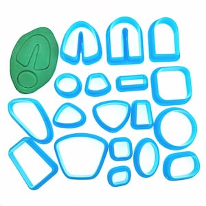May include: A set of 17 blue plastic cookie cutters in various shapes, including circles, ovals, rectangles, and triangles. There is also a green plastic cookie cutter in the shape of a leaf.