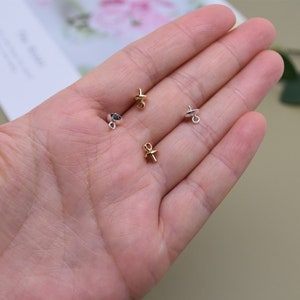 May include: Four gold and silver bead tips for jewelry making. The tips have a small loop at the top and a flat base.