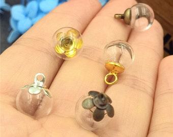 May include: Five glass bottle charms with different metal tops. The charms are clear glass and have a round shape. The metal tops are gold, silver, and bronze.
