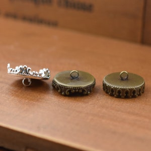 May include: Three decorative buttons with a crown-like design. The button on the left is silver, and the two buttons on the right are bronze.