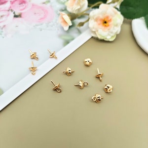 May include: Gold-toned metal bead caps with a flower design. The caps have a small loop on the top and a pointed end on the bottom.