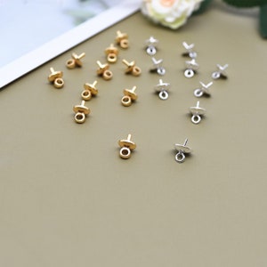 May include: A collection of gold and silver bead tips for jewelry making. The tips have a small loop at the top and a flat base with a hole for attaching a bead.