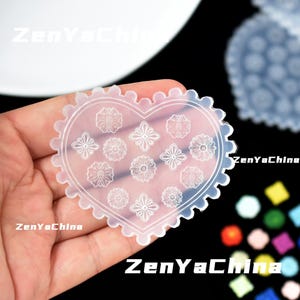 May include: A transparent, heart-shaped silicone mould with a scalloped edge and floral patterns. The mould features various flower designs and is held in a hand. The text "ZenYaChina" is visible in the image.