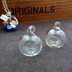 May include: Two clear glass ornaments with a small opening at the top. The ornaments have a round shape and are perfect for adding a touch of elegance to any home decor.