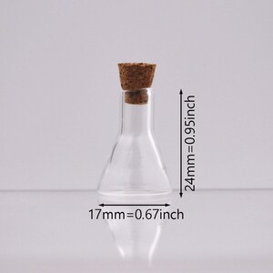 May include: A clear glass bottle with a cork stopper. The bottle is 2.4 inches tall and 0.67 inches wide.