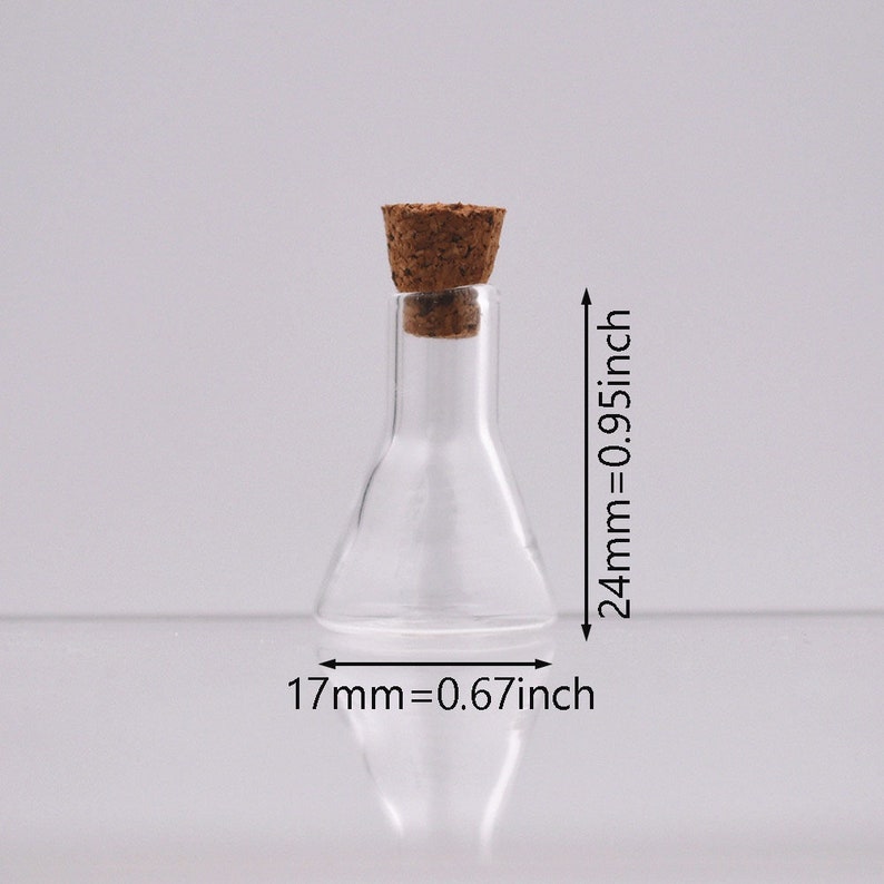 May include: A clear glass bottle with a cork stopper. The bottle is 2.4 inches tall and 0.67 inches wide.