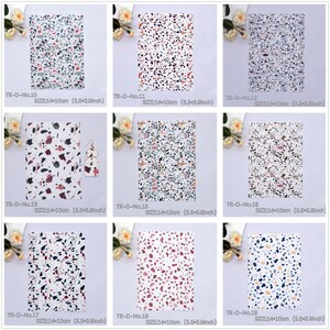 May include: Nine different patterned sheets of faux leather with a terrazzo design. Each sheet is 14 cm by 10 cm. The patterns feature various colours including white, black, grey, pink, red, and blue.