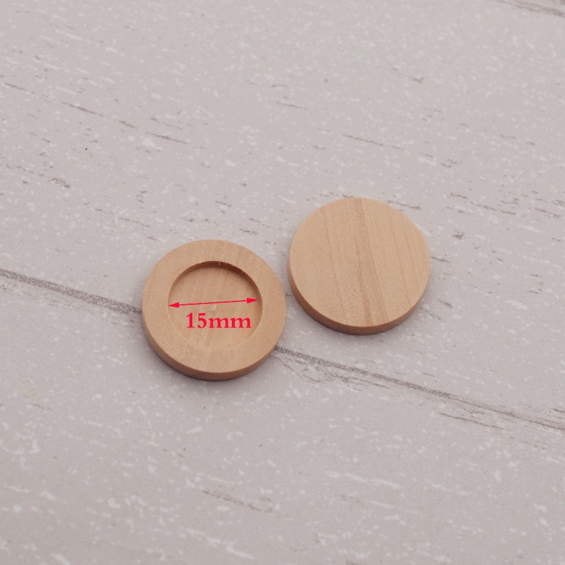 May include: Two round wooden discs, one with a 15mm diameter hole in the center. The discs are made of light brown wood and are perfect for crafting projects.