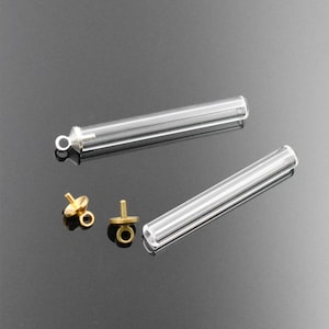 May include: Two clear glass tubes with gold metal caps and two gold metal jump rings. The tubes are approximately 5 cm long.