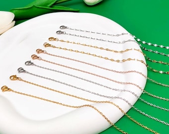 May include: A set of ten delicate chain necklaces in silver, gold, and rose gold. The chains are all the same length and have a lobster clasp closure. ZenYaChina is printed on the white surface below the chains.