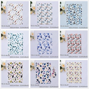 May include: Nine different patterned fabric sheets with a terrazzo design. Each sheet is 14 cm by 10 cm. The patterns feature various colours, including blue, green, red, brown, and white.