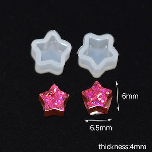 以下が含まれることがあります： 樹脂製のジュエリーを作るための、透明なシリコン製の星型のモールド2個。モールドは幅6.5mm、高さ6mm。モールドは、幅6.5mm、高さ6mm、厚さ4mmの完成した樹脂製の星2個と一緒に示されています。