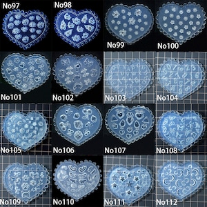 May include: A selection of clear, heart-shaped moulds with scalloped edges. Each mould showcases a unique design, such as flowers, stars, numbers, and other shapes. The moulds are labelled from No97 to No112.