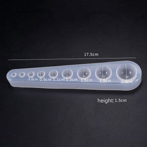 May include: Clear silicone mold with seven round cavities for making resin spheres. The mold measures 17.5 inches long and 1.5 inches high. The cavities are 0.8, 0.9, 1.1, 1.3, 1.5, 1.9, and 2.4 inches in diameter.