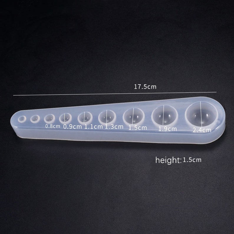 May include: Clear silicone mold with seven round cavities for making resin spheres. The mold measures 17.5 inches long and 1.5 inches high. The cavities are 0.8, 0.9, 1.1, 1.3, 1.5, 1.9, and 2.4 inches in diameter.
