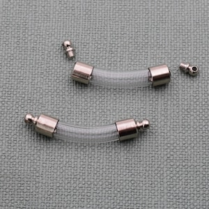 May include: Two clear glass tubes with silver metal caps and ball ends. The tubes are curved and are separated from each other.
