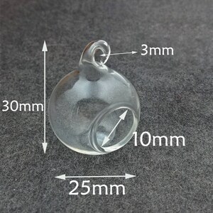 May include: A clear glass globe with a 3 mm opening at the top. The globe is 25 mm wide and 30 mm tall. The opening is 10 mm in diameter.