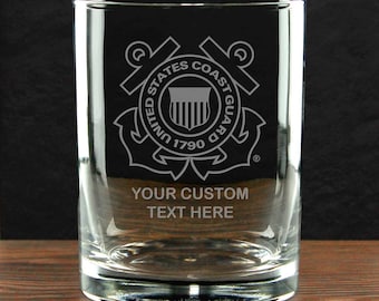 May include: A clear glass tumbler featuring an etched United States Coast Guard emblem with the text 1790 and the words YOUR CUSTOM TEXT HERE engraved below the logo. The glass has a cylindrical shape with a thick base and smooth walls.