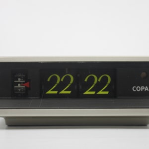 Può includere: Un orologio a lembo nero e grigio con un cavo verde. L'orologio mostra l'ora 22:22 e ha la scritta "COPAL" stampata sul davanti.
