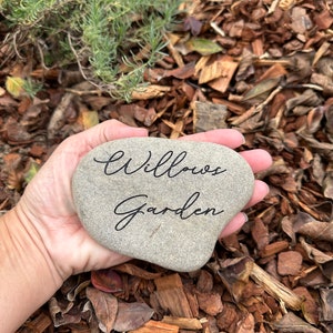 Pu&ograve; includere: Una pietra grigia a forma di cuore con le parole "Willow's Garden" incise in corsivo nero.