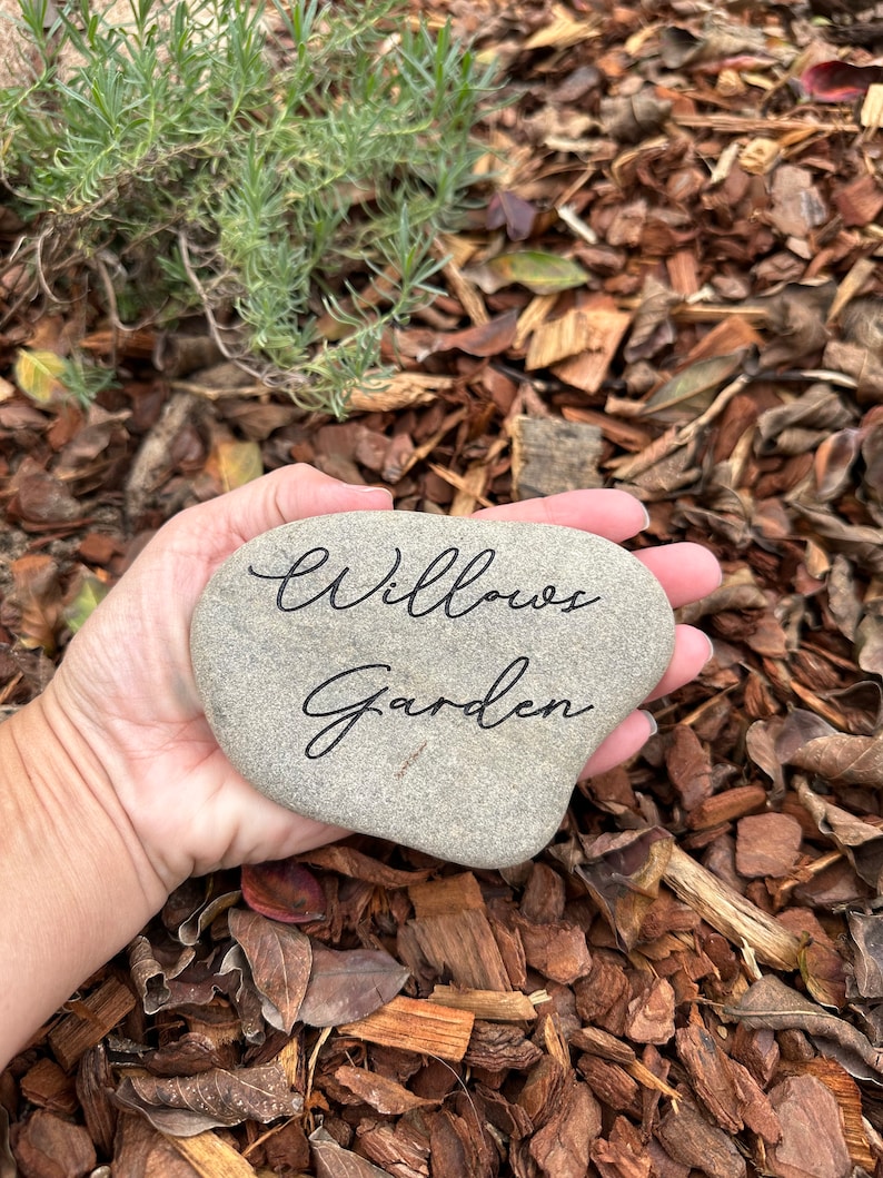 Pu&ograve; includere: Una pietra grigia a forma di cuore con le parole "Willow's Garden" incise in corsivo nero.