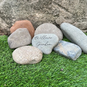 Pu&ograve; includere: Una collezione di pietre grigie, marroni e bianche su una superficie di erba artificiale verde. Una pietra ha le parole "Willow Garden" scritte su di essa.