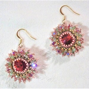 May include: A pair of pink and gold beaded earrings with a large red crystal in the center of each earring.