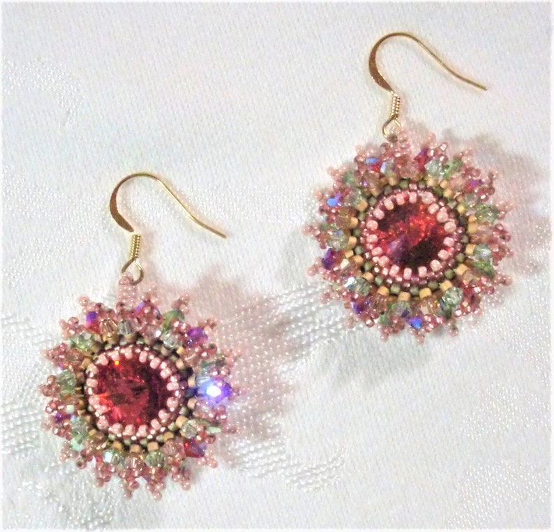 May include: A pair of pink and gold beaded earrings with a large red crystal in the center of each earring.