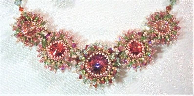 May include: A delicate necklace with five pink and green flower-shaped clusters of beads, each with a sparkling red crystal in the center.
