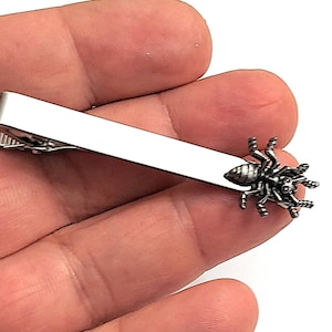 May include: Silver tie bar with a detailed spider design.