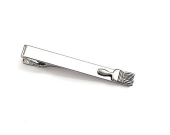 Può includere: Fermacravatta argentato con un design dettagliato a pennello. La clip è rettangolare con finitura lucida, e il pennello è scolpito sul lato destro. Un accessorio elegante per artisti o creativi.