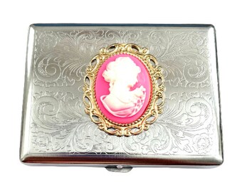 May include: A silver cigarette case with an engraved floral design and a pink cameo with a gold frame.