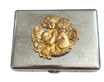May include: Silver cigarette case with an ornate design and a gold-toned embossed image of two angels embracing.