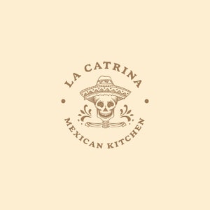 Może przedstawiać: Brązowo-białe logo z tekstem "La Catrina Mexican Kitchen" w k&oacute;łku. Logo przedstawia czaszkę w sombrero.