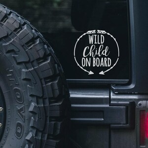May include: A black car with a white vinyl sticker on the rear window that says "Wild Child On Board" in a circle with arrows pointing out.